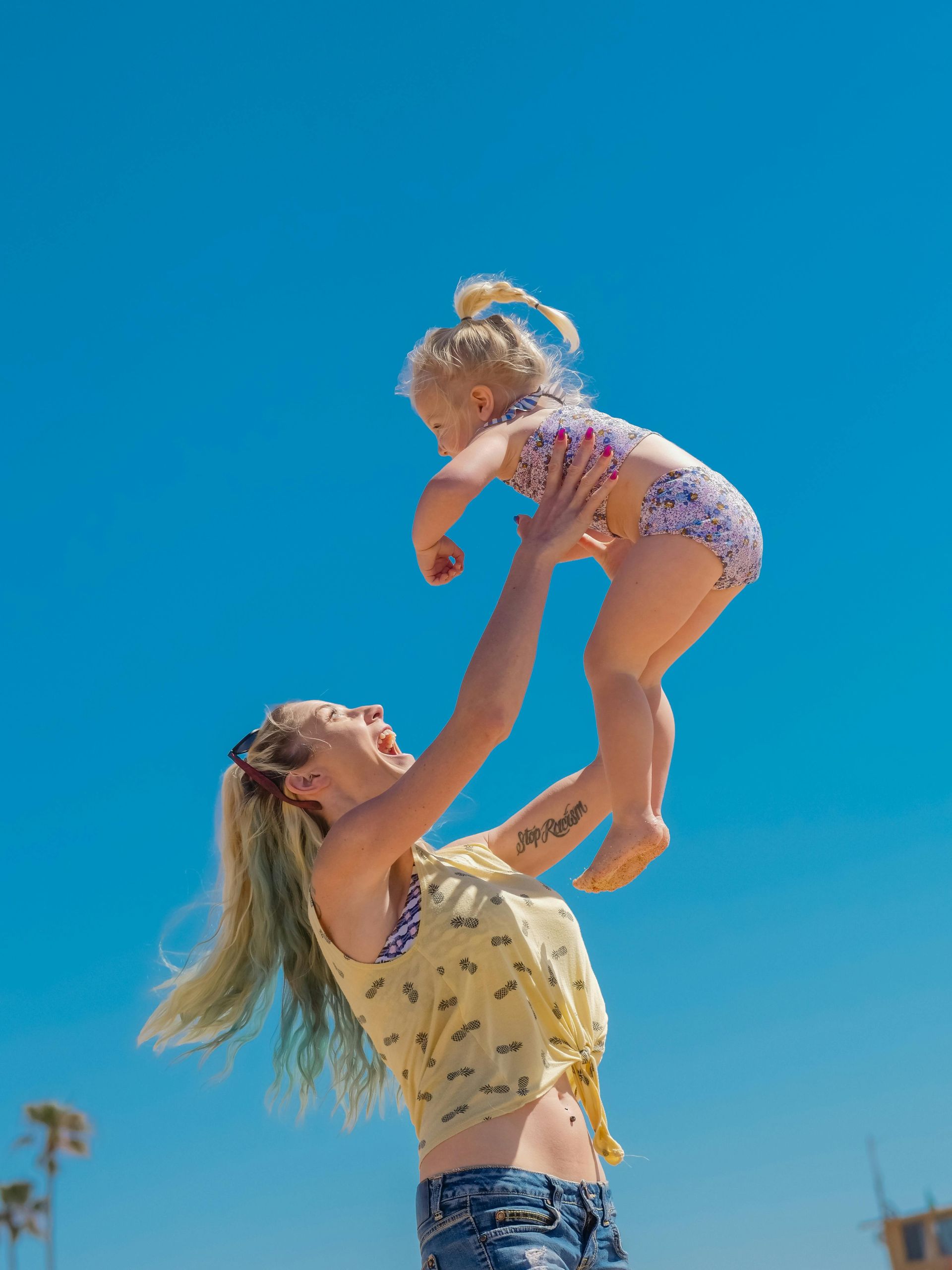A woman is holding a little girl in the air.