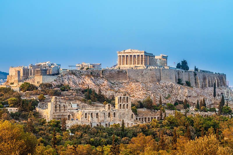 Acropolis of Athens with Parthenon atop a hill, bathed in warm sunlight.