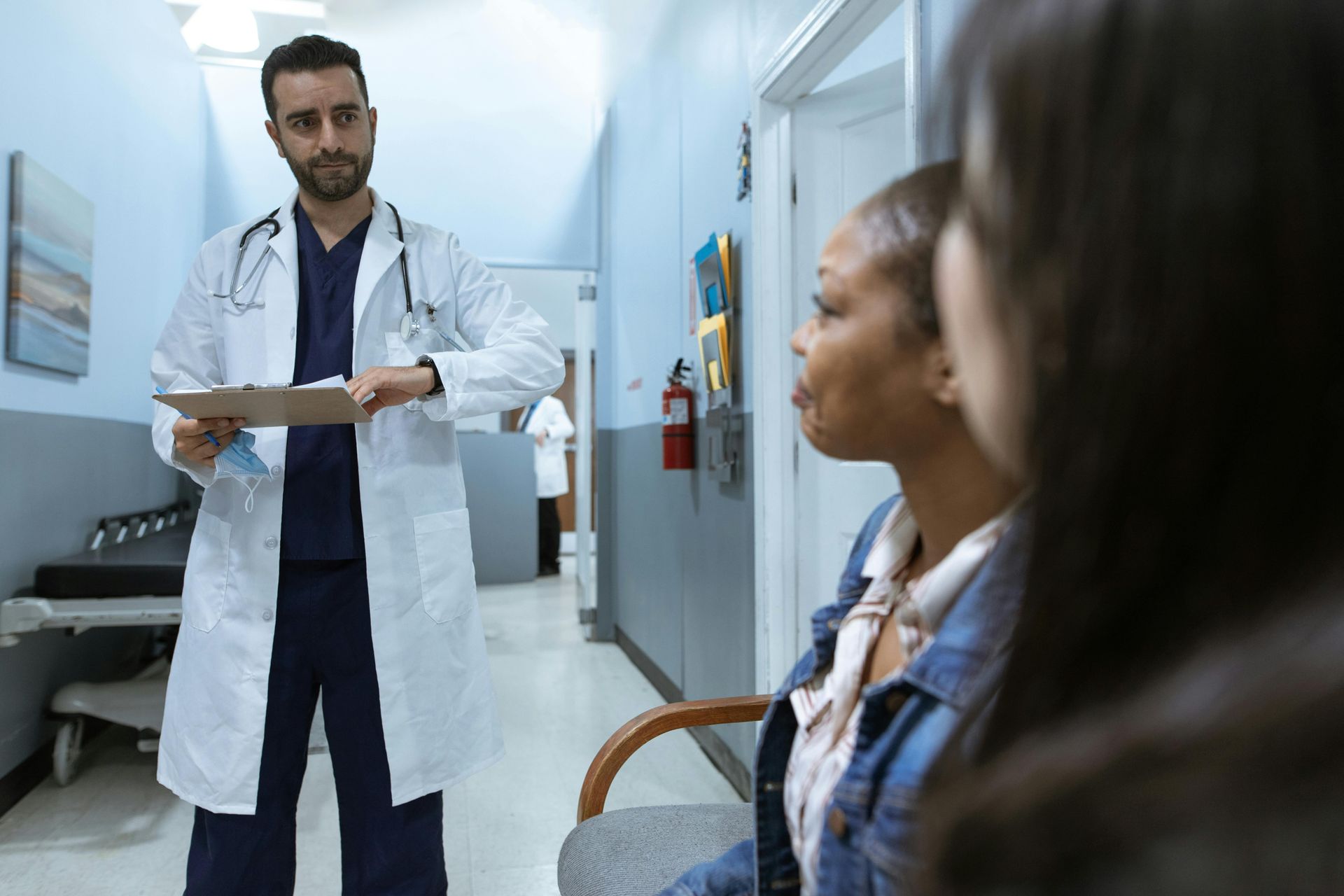 A doctor is talking to a patient in a hospital hallway.