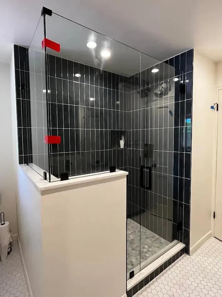 A bathroom with a walk in shower with a glass door.