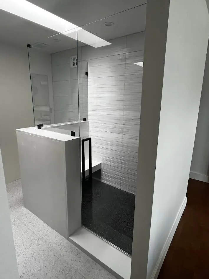 A bathroom with a walk in shower and a black floor.