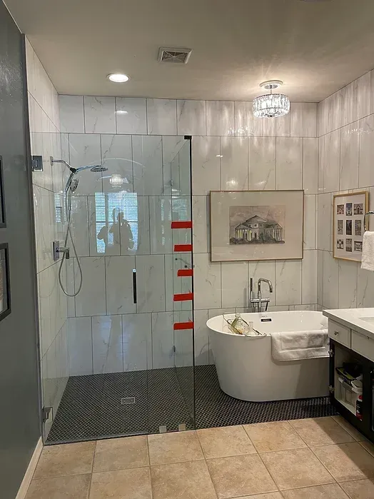 A bathroom with a tub , sink , shower and walk in shower.