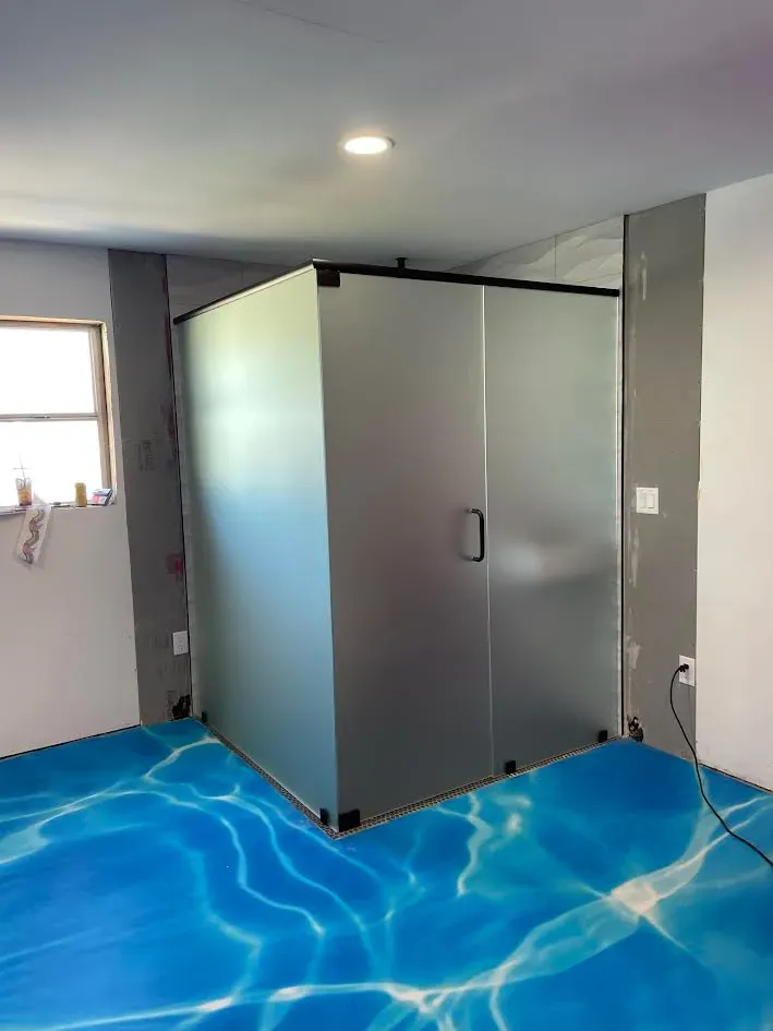 A bathroom with a blue floor and a shower stall.