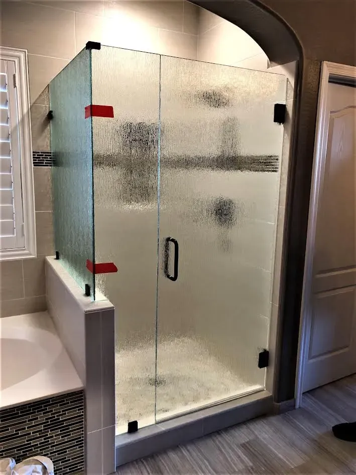 A bathroom with a walk in shower with a glass door.