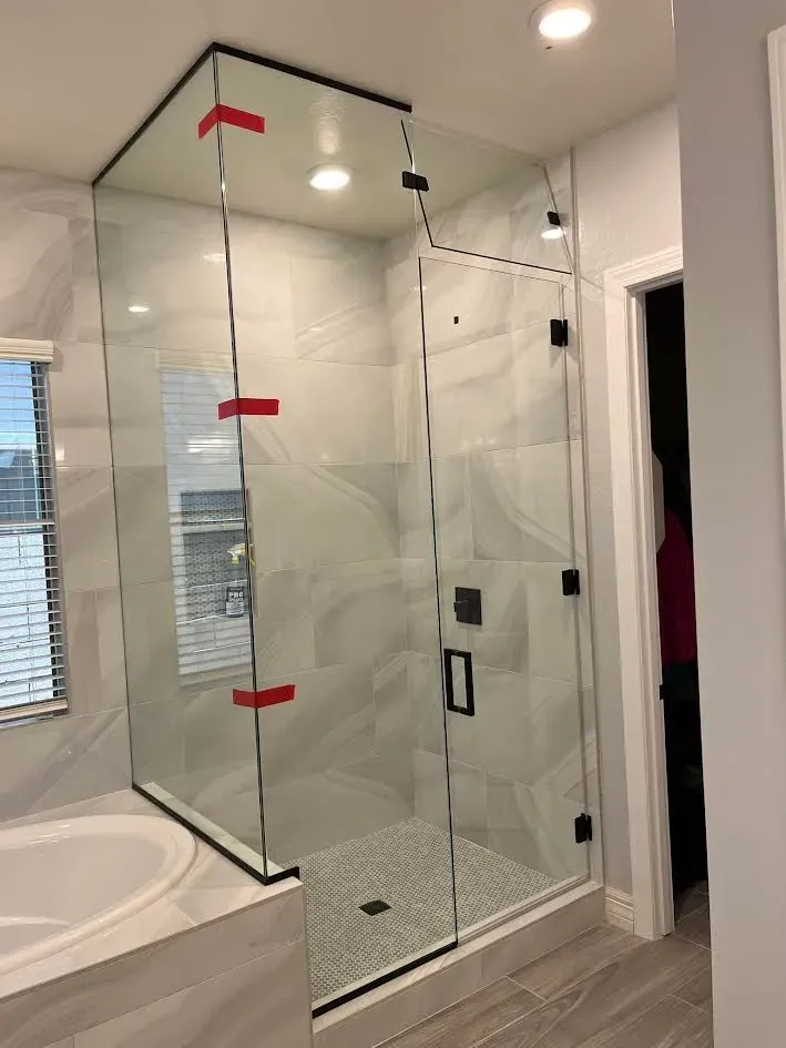 A bathroom with a walk in shower and a tub.