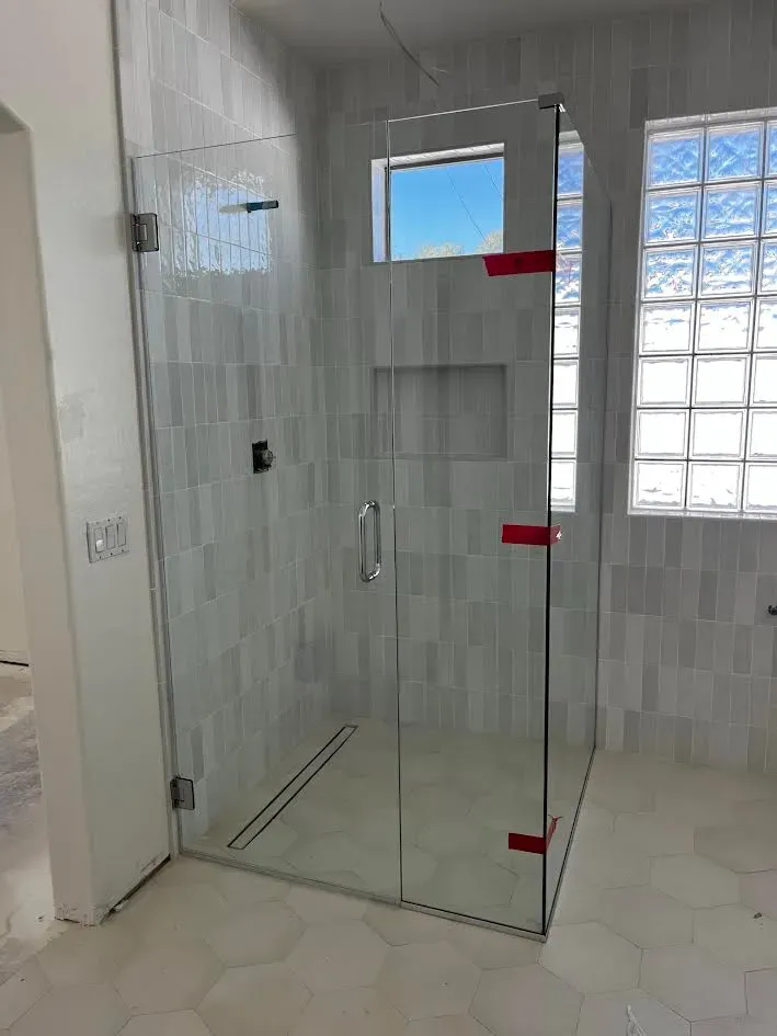 A bathroom with a shower stall and a window.