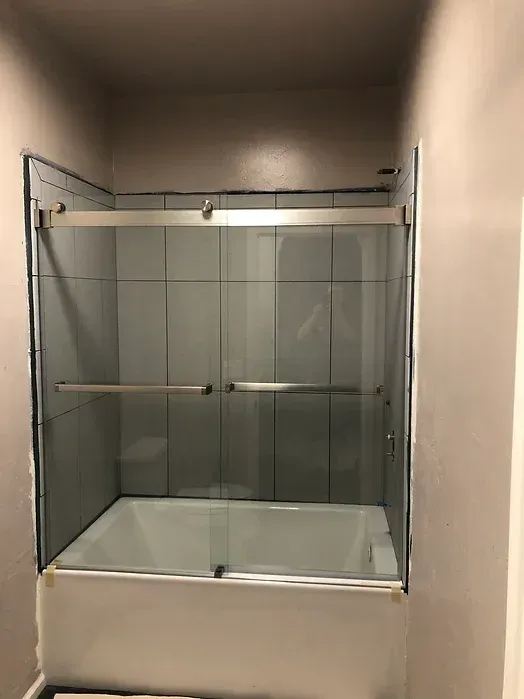 A bathroom with a bathtub and a glass shower door.