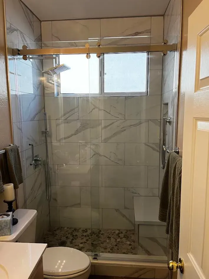 A bathroom with a toilet , sink , shower and window.