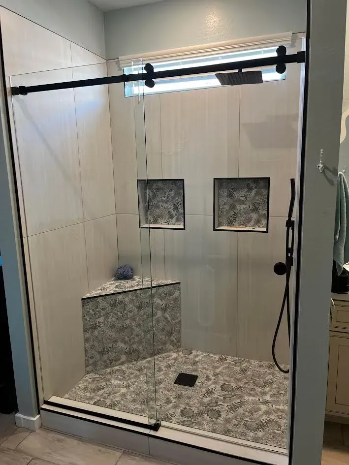 A bathroom with a walk in shower with a sliding glass door.