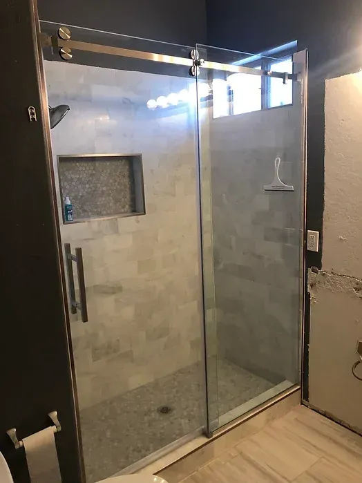 A bathroom with a sliding glass shower door.
