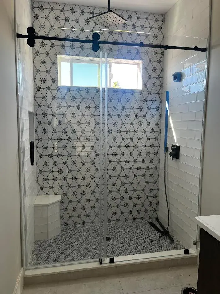 A bathroom with a sliding glass shower door and a window.