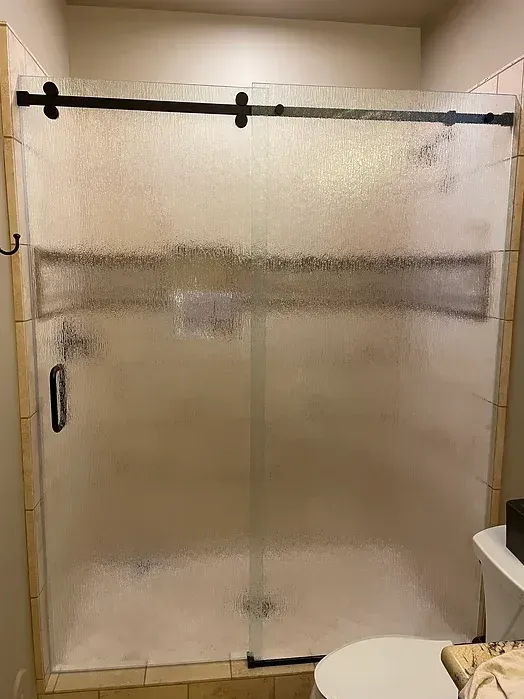 A bathroom with a sliding glass shower door and a toilet.