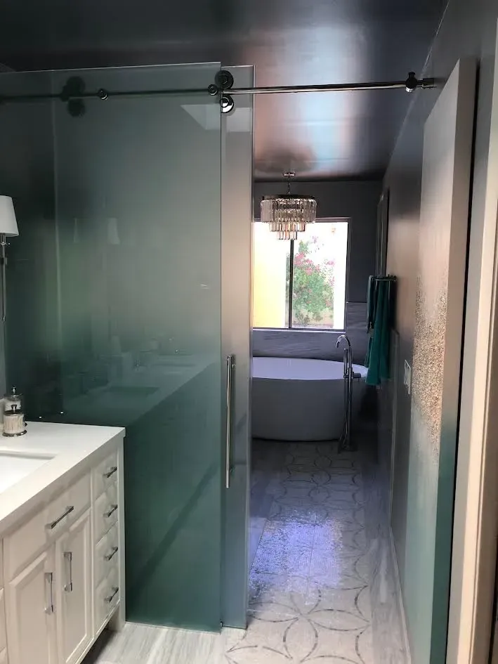 A bathroom with a sliding glass door leading to a bathtub.