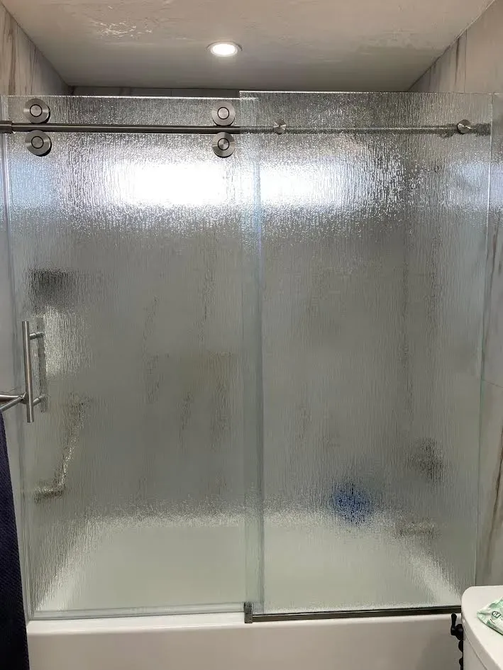 A bathroom with a bathtub and a sliding glass shower door.