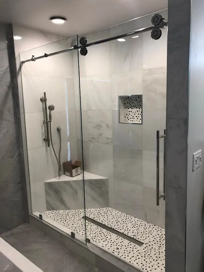 A bathroom with a sliding glass shower door.
