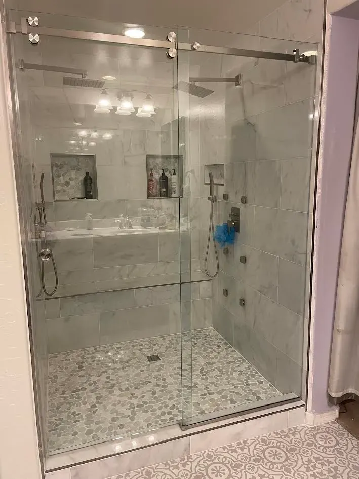 A bathroom with a walk in shower with sliding glass doors.