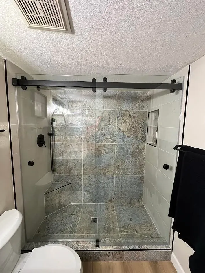 A bathroom with a sliding glass shower door and a toilet.