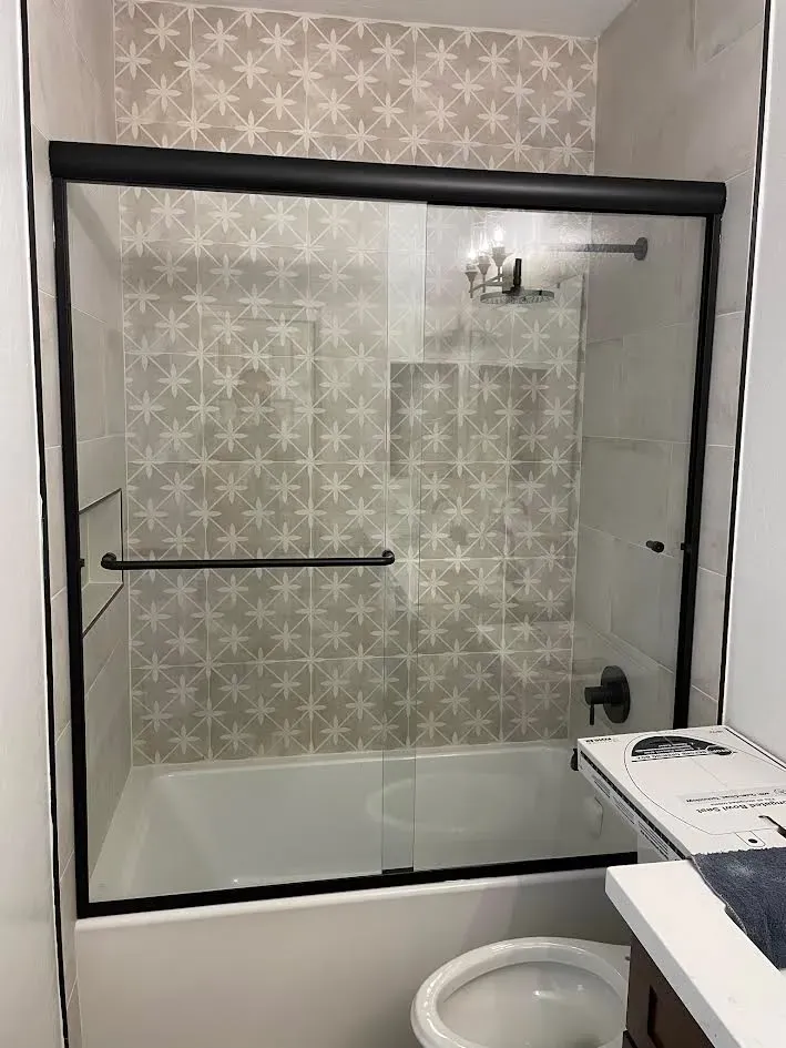 A bathroom with a sliding glass shower door and a bathtub.