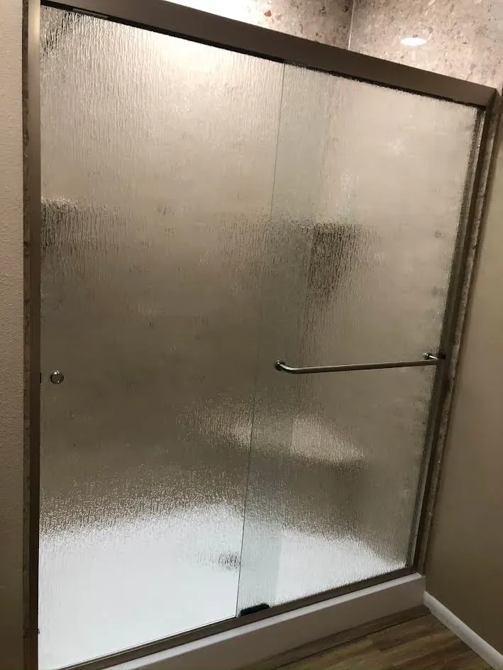 A bathroom with a sliding glass shower door and a bathtub.