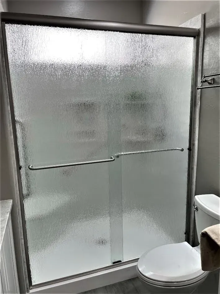 A bathroom with a sliding glass shower door and a toilet.