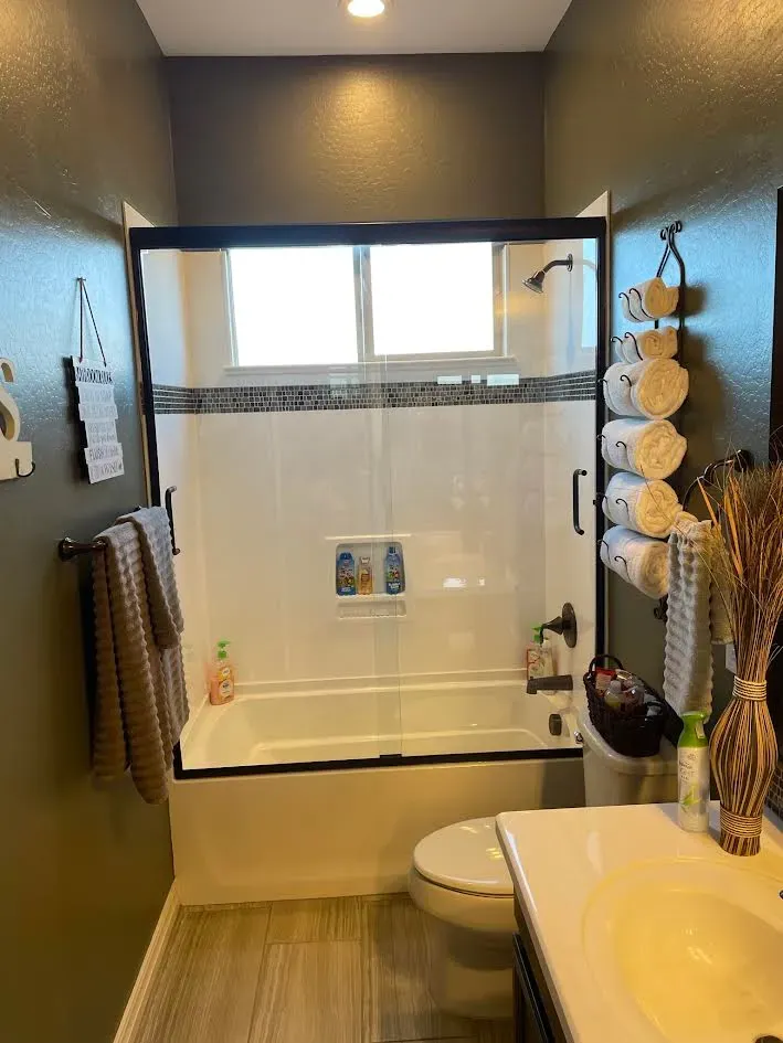 A bathroom with a tub , toilet , sink and window.