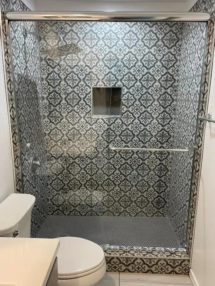 A bathroom with a toilet , sink and shower with a sliding glass door.