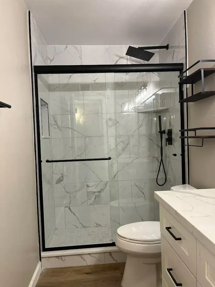 A bathroom with a toilet , sink and shower.