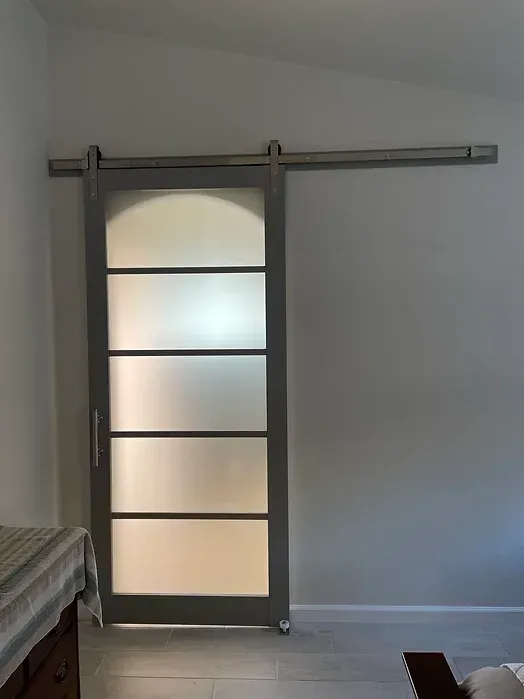 A bedroom with a sliding barn door with frosted glass