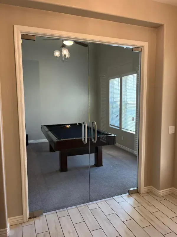 A pool table in a room with a glass door