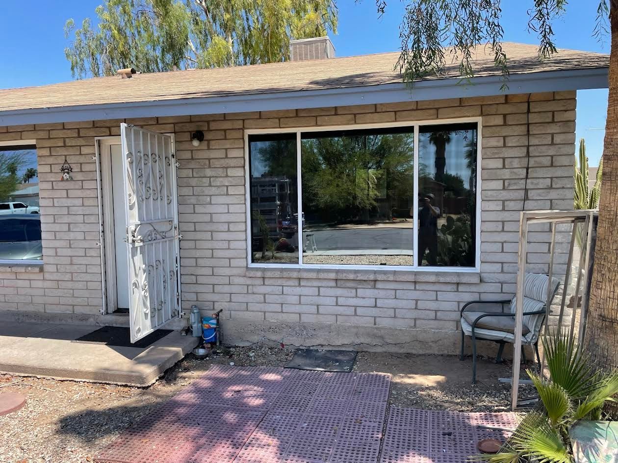 A white brick house with a large window and a chair in front of it.