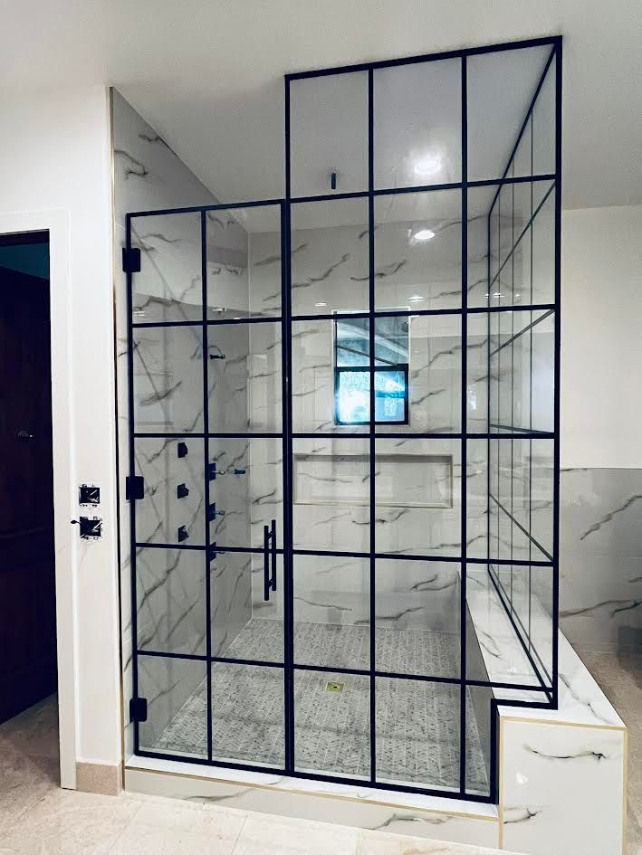 A bathroom with a walk in shower with a black frame.