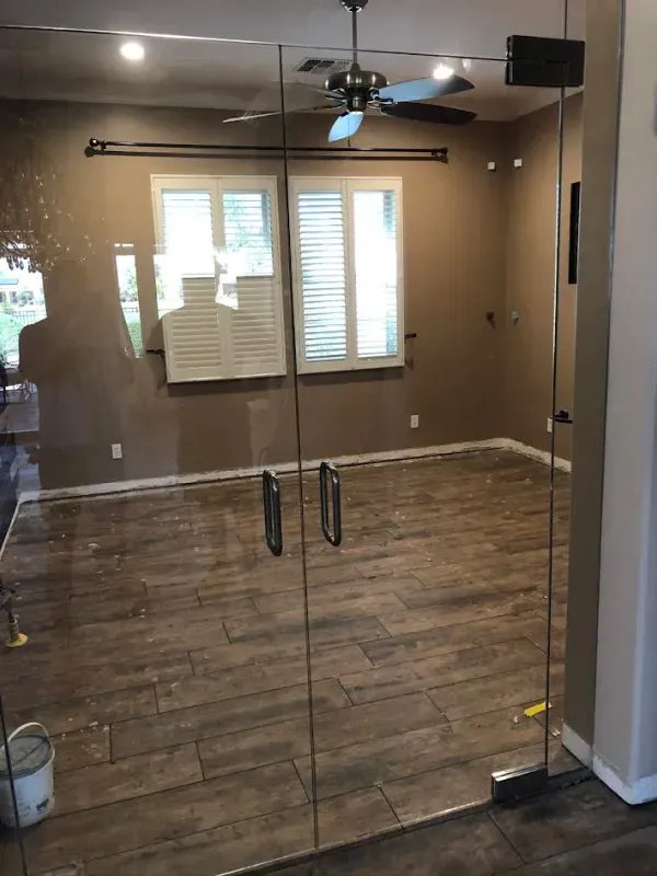 A living room with a ceiling fan and a glass door.
