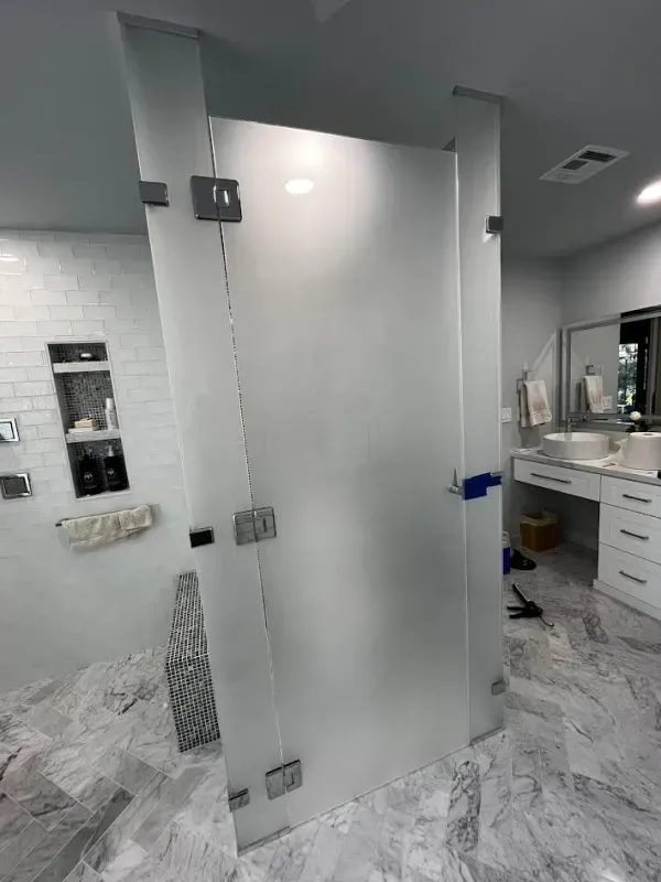A bathroom with a glass shower door and a sink.