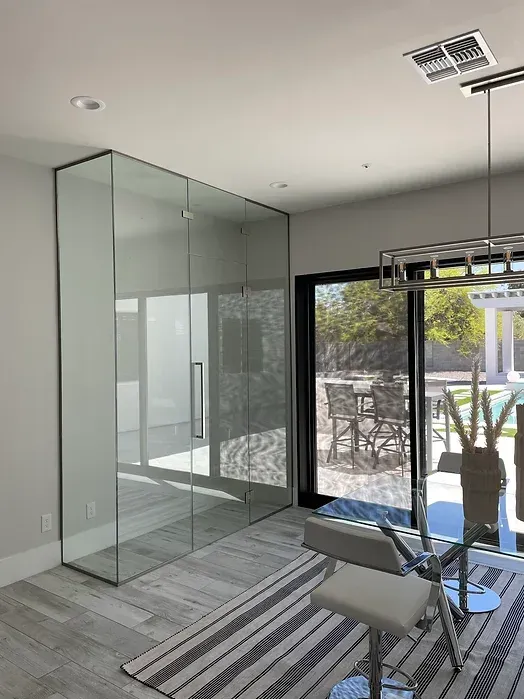 A dining room with a glass wall and sliding glass doors.