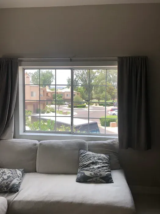 A living room with a couch and a window with curtains.