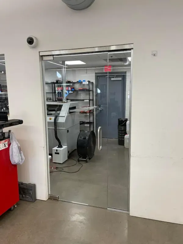 A glass door is open to a room with a machine in it.