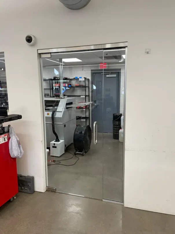 A glass door is open to a room with a machine in it.