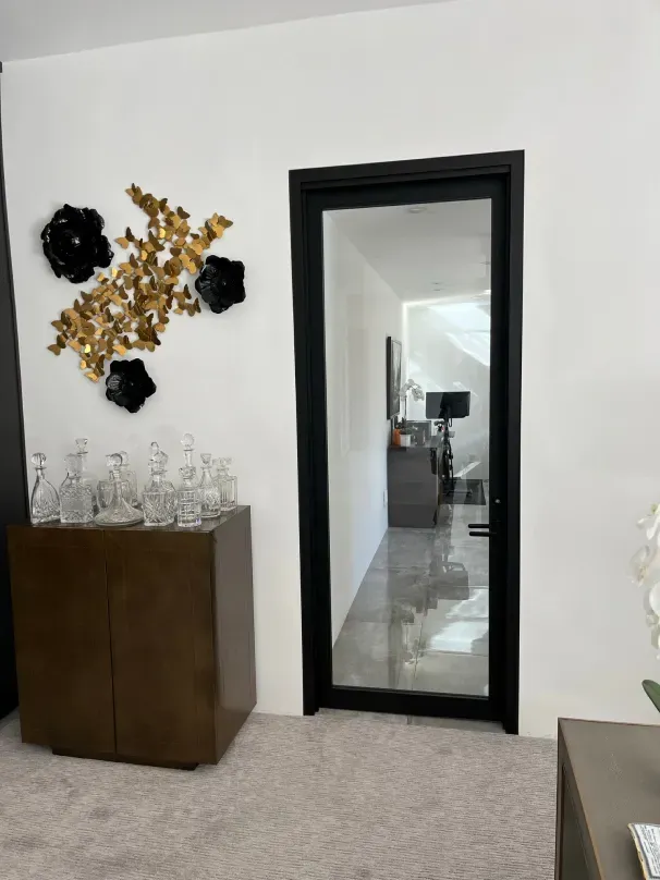 A living room with a black door and a mirror on the wall.