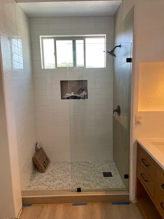 A bathroom with a walk in shower and a window.