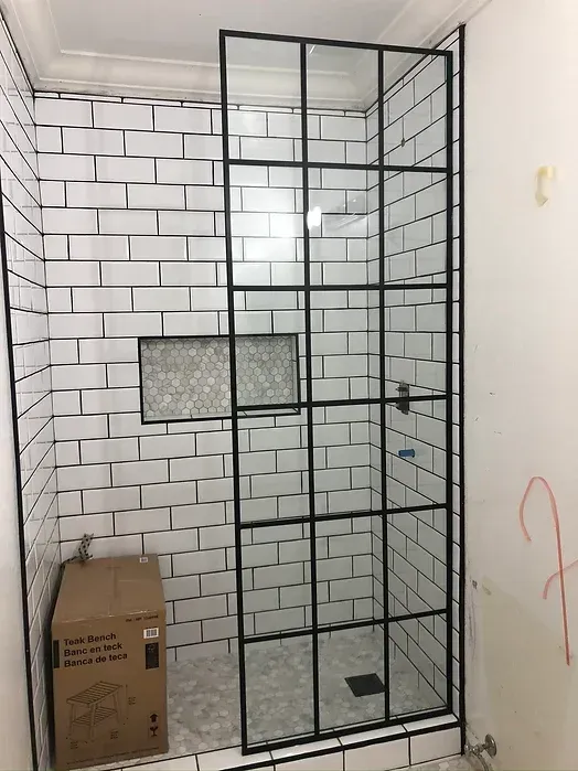 A bathroom with white subway tiles and a black shower door.