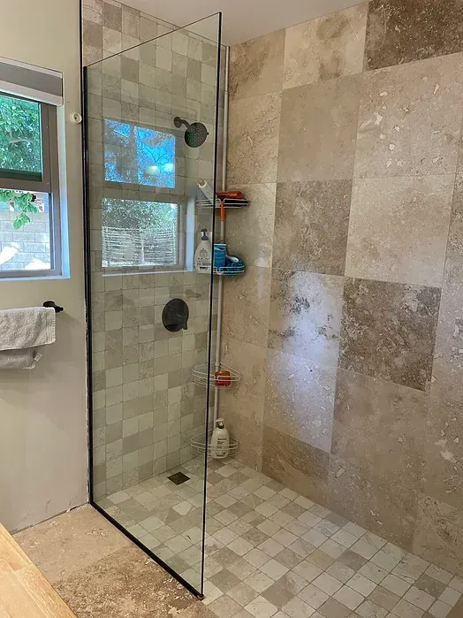 A bathroom with a walk in shower and a window.