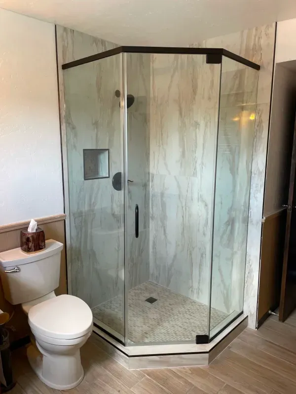 A bathroom with a toilet , shower and glass door.