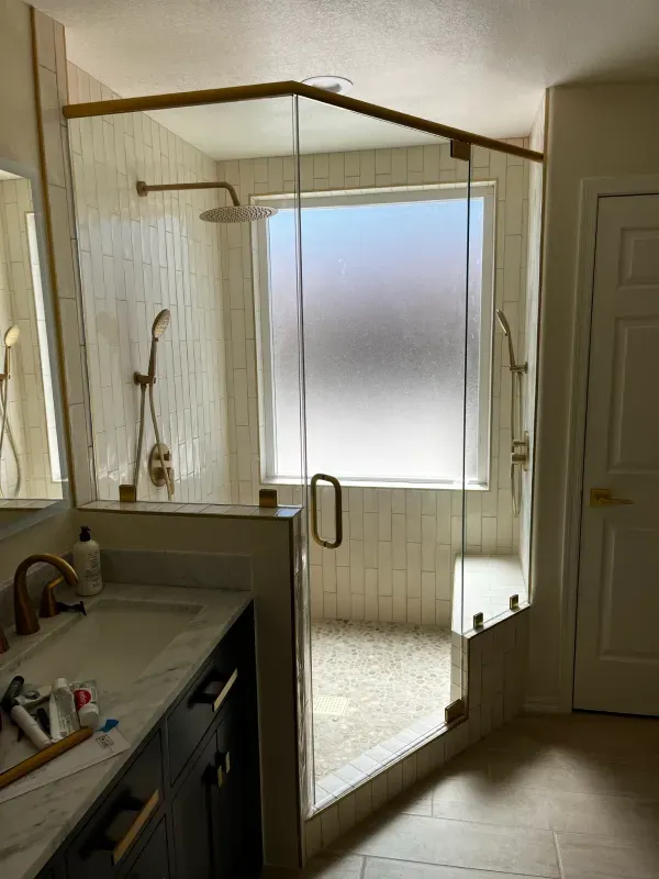 A bathroom with a walk in shower and a sink.