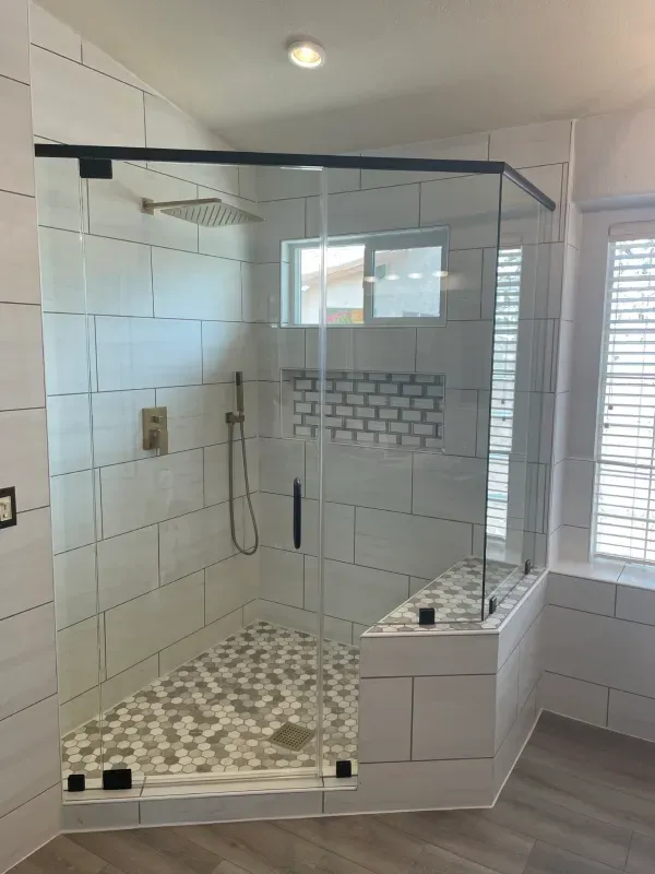 A bathroom with a walk in shower with a glass door.