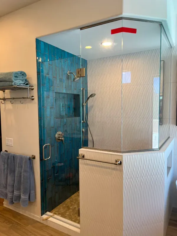 A bathroom with a walk in shower with a glass door.