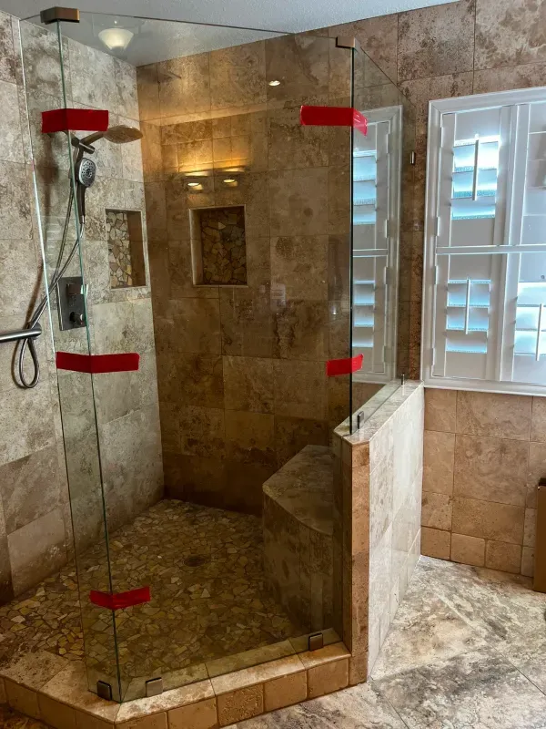 A bathroom with a walk in shower with a glass door.