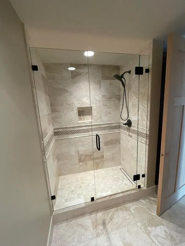 A bathroom with a walk in shower with a glass door.