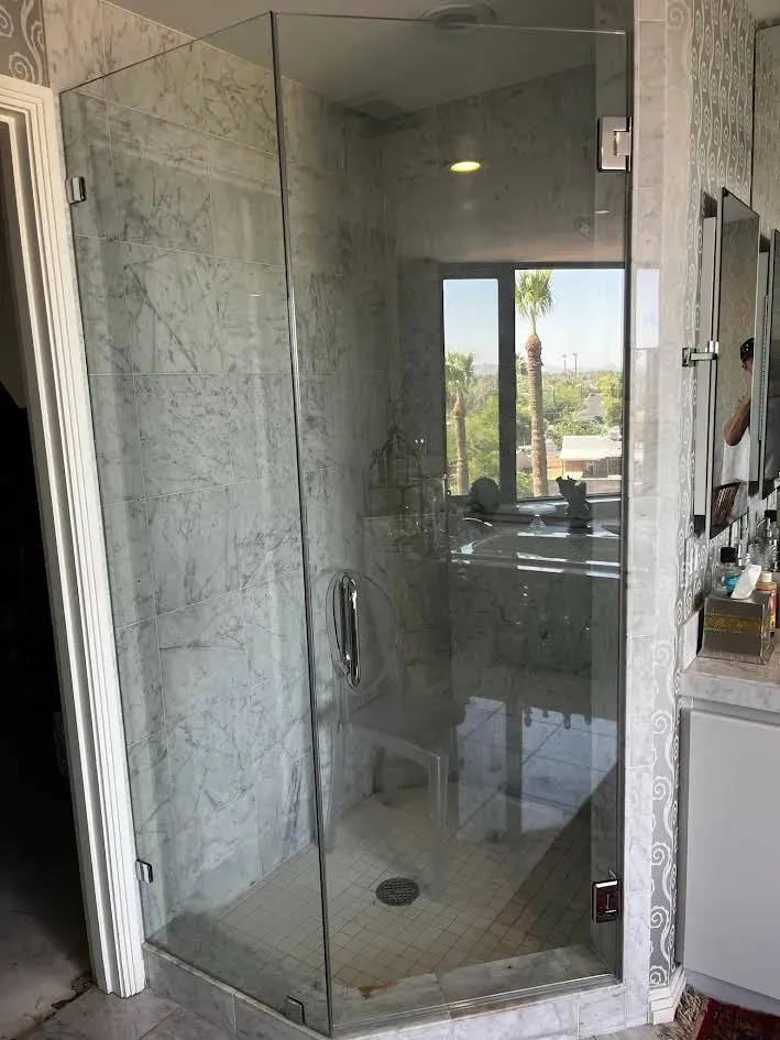 A bathroom with a glass shower door and a window.
