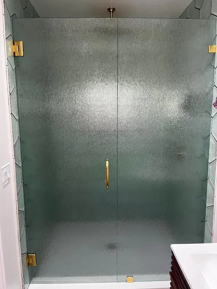 A bathroom with a glass shower door and a sink.