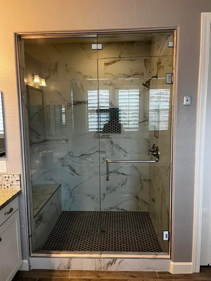 A bathroom with a walk in shower with a glass door.